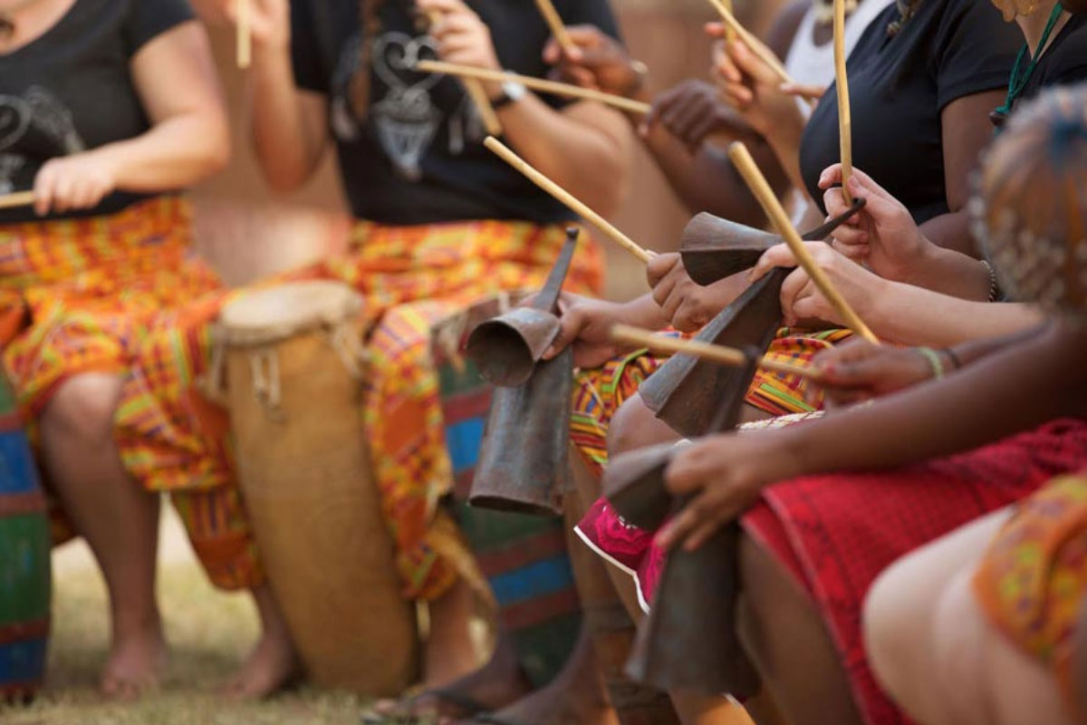 Students taking part in a cultural music session with traditional drums and hand instruments