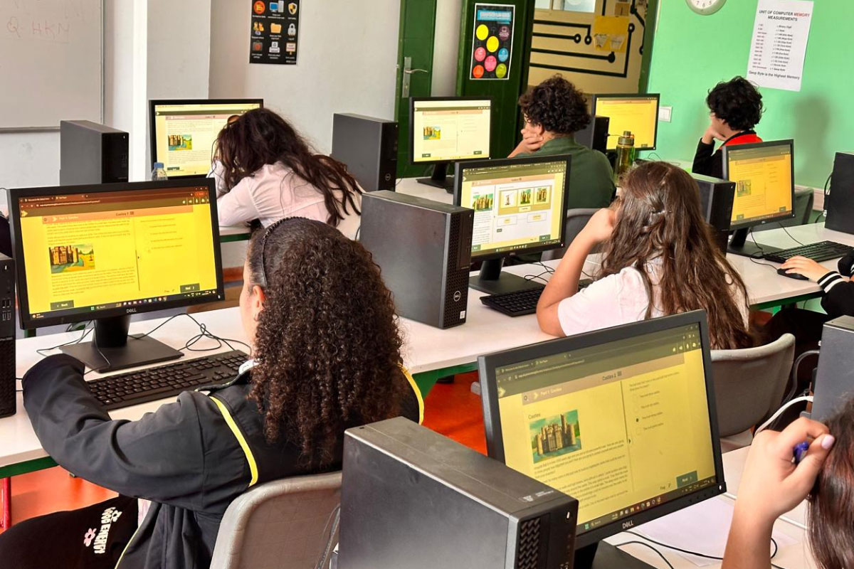 Students in a computer lab working on desktop screens during a digital learning lesson