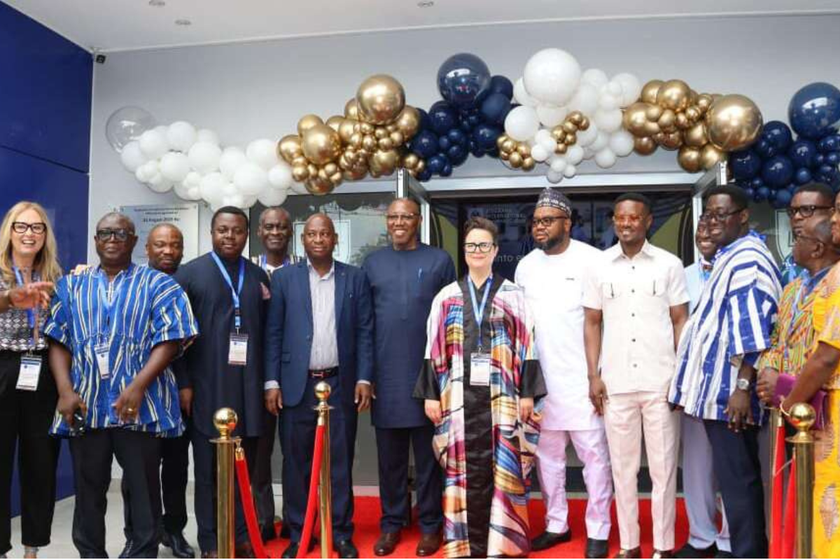 School leaders and guests standing at a campus entrance during an opening event with balloon decorations