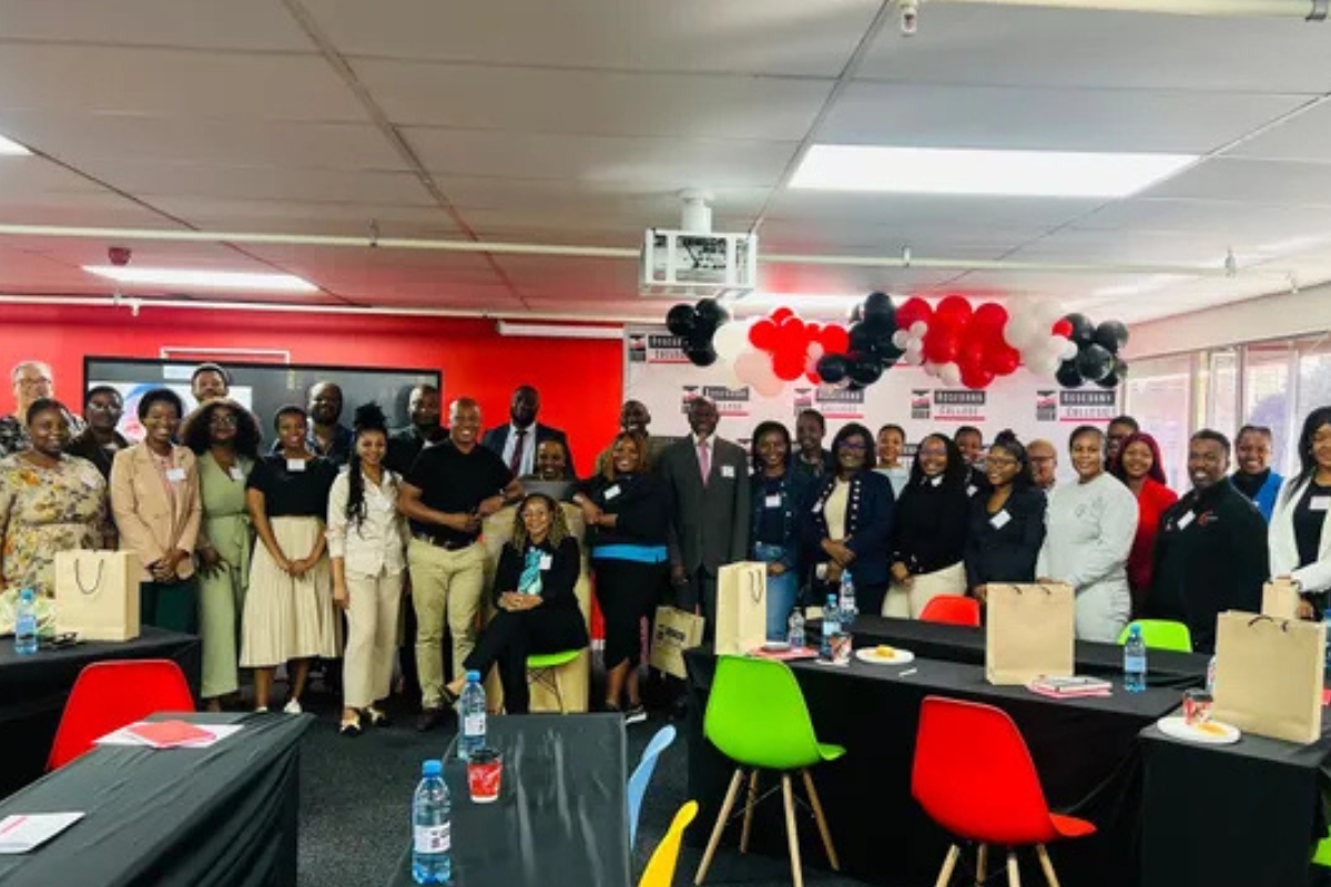 Educators and school leaders standing together at an indoor event with group tables and banners