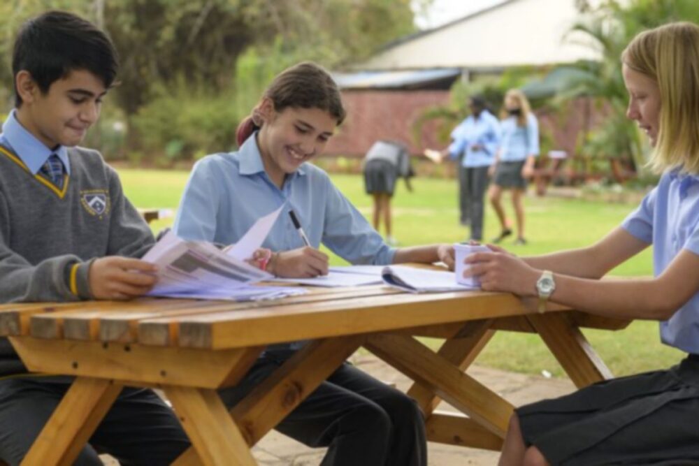 Three senior students studying together outdoors at a garden table