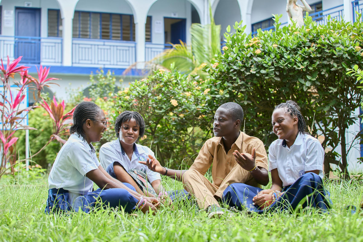 Students sitting together and talking in a garden area on a school campus in Nigeria