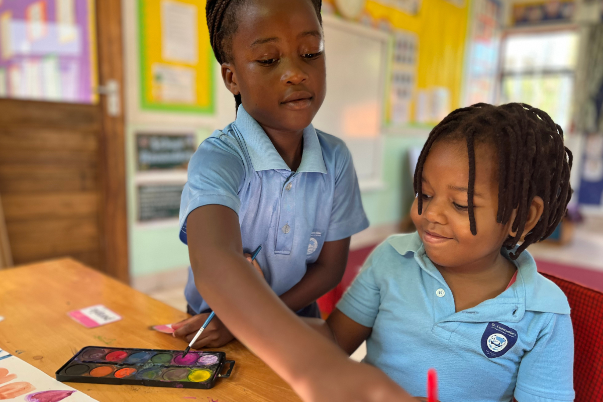 Two pupils in art class sharing paint and working together on a creative task